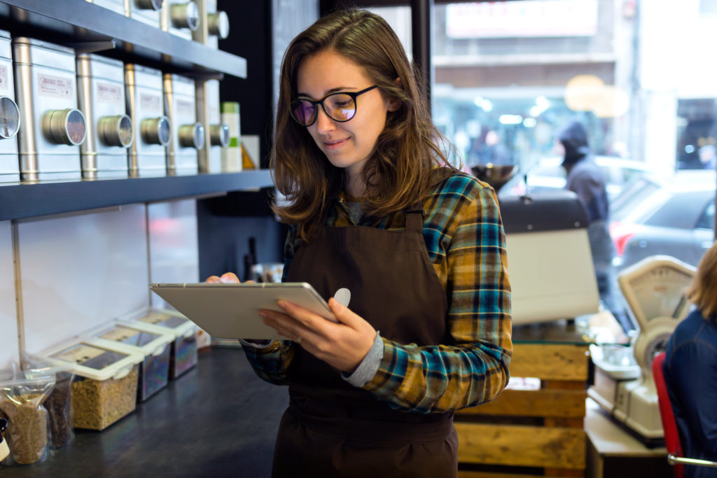 Portrait of beautiful young saleswoman doing inventory in a retail store selling coffee.